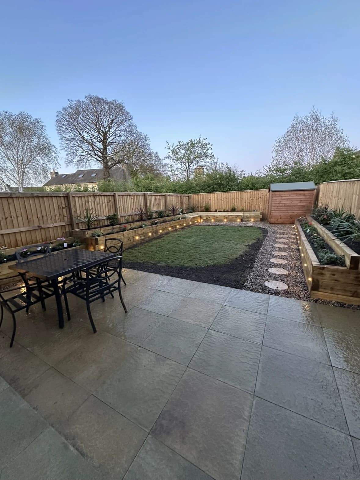 Elevated view of a garden with a paved patio, lawn, stepping stones and timber raised beds